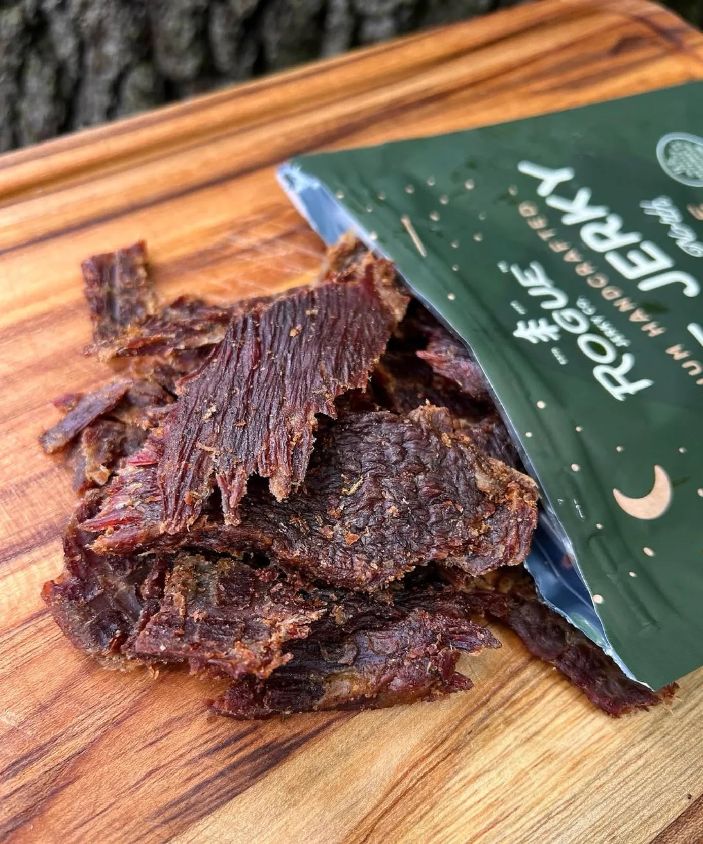 Roque Jerky on a wooden cutting board with a green packaging.